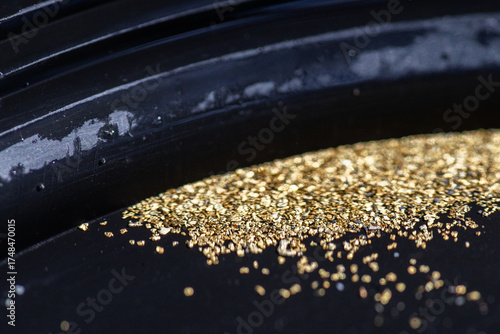 Wallpaper Mural Closeup view of gold flakes collected in a black panning pan. Shiny metallic particles representing mining, prospecting, natural resources, and the search for wealth and treasure. Torontodigital.ca