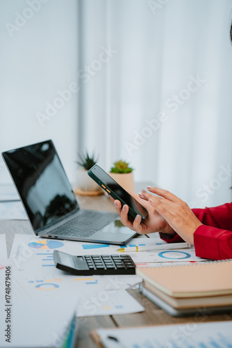 Smiling businesswoman talking on phone and holding tablet while working with documents and laptop in office