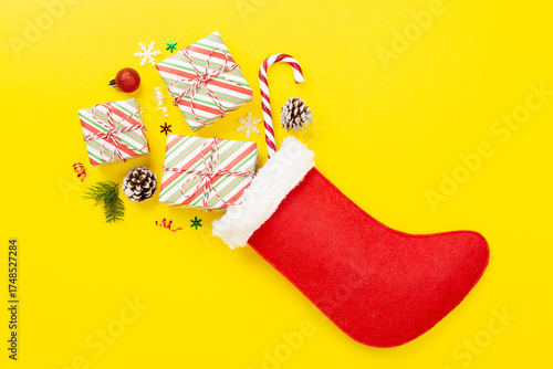 Christmas sock with gifts and decoration on color background, top view