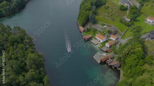Scenic aerial view of small coastal village with boat leaving harbor