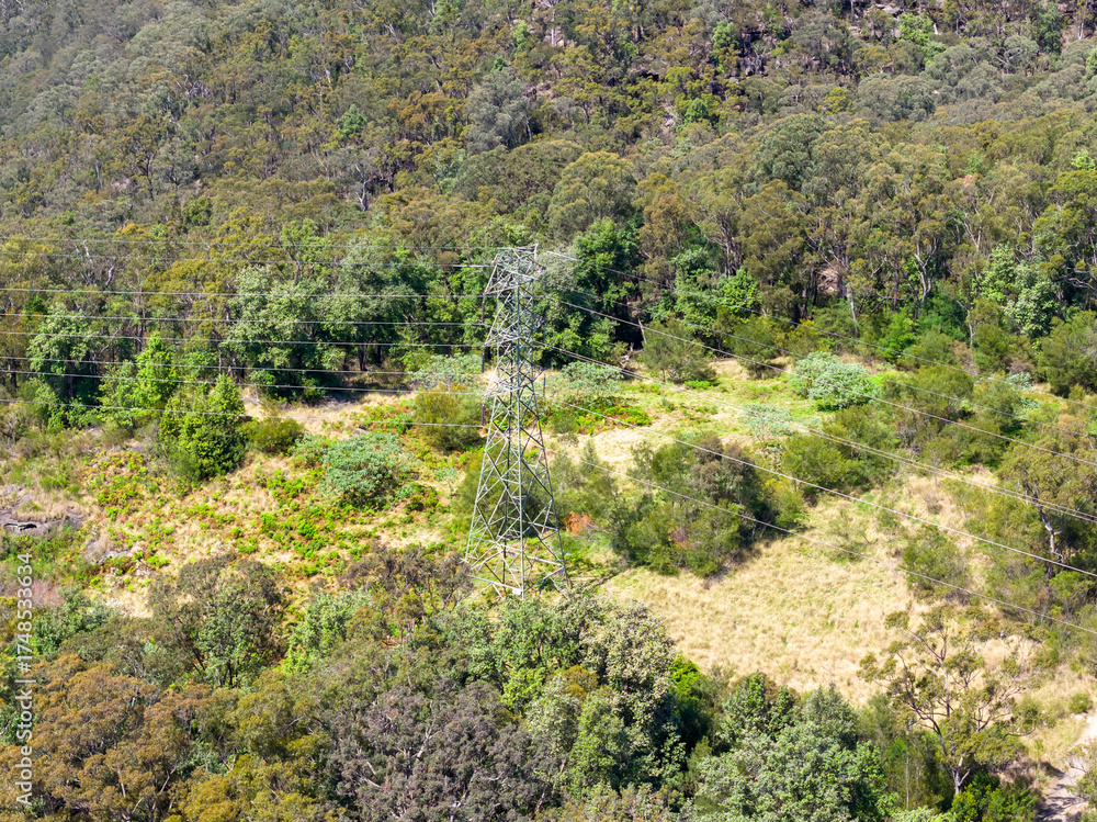 Naklejka premium Drone aerial photograph of an electrical transmission tower running through regional bushland in the Blue Mountains in NSW, Australia.