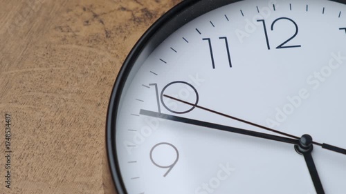 A close-up view of a minimalist clock design, showcasing its elegant features against a wooden backdrop.