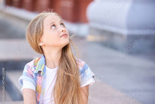Φωτογραφία Caucasian young girl with long blonde hair looking upwards outdoors in casual attire