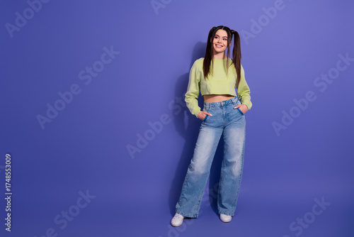 Fototapeta Stylish young woman with trendy casual fashion outfit posing confidently on a pu