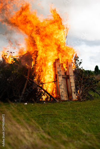 Large local bonfire on grass field vertical view and intense burning.