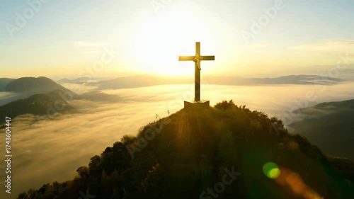 Silhouetted crucifix mountain summit sunrise, golden rays halo cross, distant mountains in soft mist, clouds birds flying Christian ultra-realistic cinematic 4K aerial cinematic sweep, serene mood