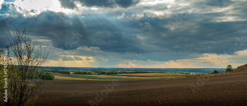 beautiful panorama of plowed land with fields, forests on the horizon, sun ra...