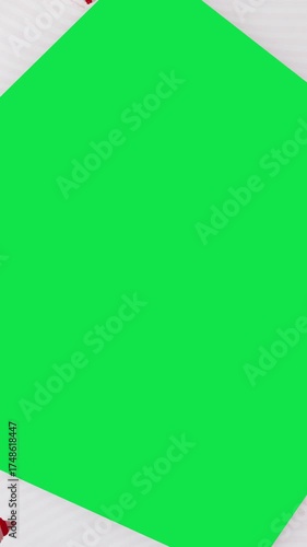 Unwrapping gift revealing a green screen - Stop Motion Animation - Red bow on Christmas wrapping paper. Vertical Screen Orientation Video