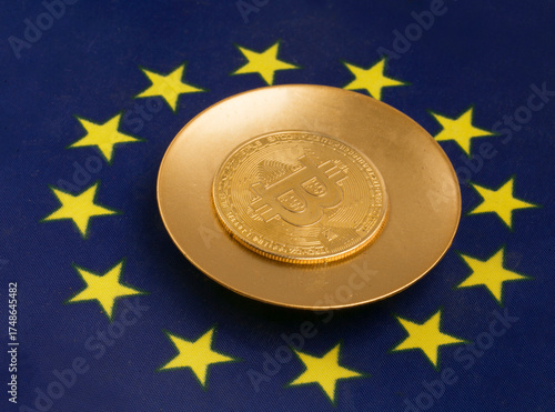 A gold plate with a Bitcoin cryptocurrency against the backdrop of the European Union flag. Concepts of the crypto EU