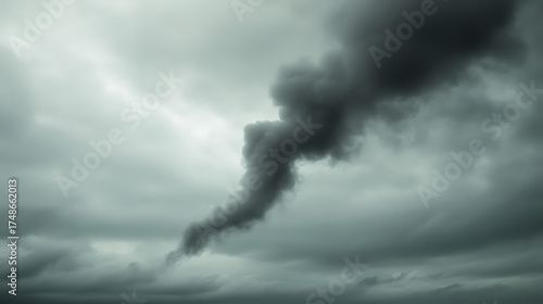 Dark smoke rises amidst a sky filled with heavy, ominous clouds, creating a scene of foreboding and uncertainty. Contrast and drama in nature.