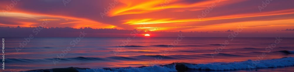 Fototapeta premium Fiery sunset paints the ocean sky with vibrant oranges, pinks, and purples, reflecting on calm water, sea, coastal