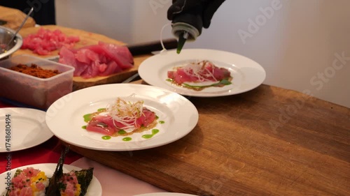 Chef drizzles sauce and spices over plates of fresh tuna salad