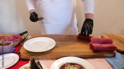 A chef expertly cuts fresh tuna with precision surrounded by full of delicious dishes