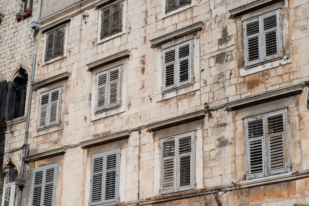 Fototapeta premium Aged stone building with gray wooden window shutters