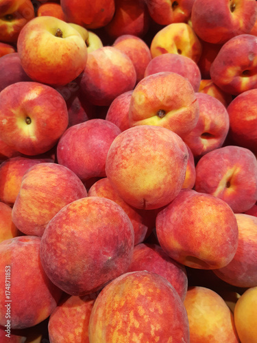 Close-up of organic red peaches in bulk. Natural fruit background. Healthy eating. Wicker basket with freshly picked peaches for sale.