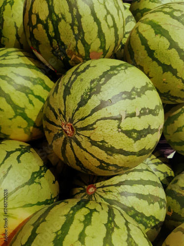 Close-up of whole organic watermelons in bulk. Natural fruit background. Healthy eating. Freshly picked watermelons for sale.