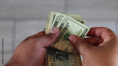 Male hands quickly counting a mixed stack of american dollar and mexican peso banknotes