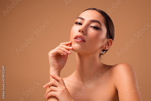 Tender portrait of a young woman highlighting beauty and style with flawless skin and a beige background