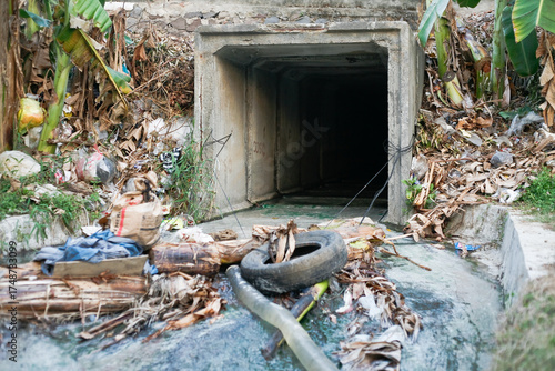 dirty exit point of the drainage channel with rubbish and car tires