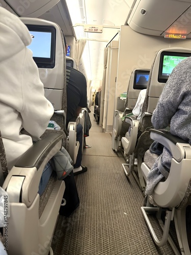 Inside View of Airplane Cabin Rows with Passengers and Aisle