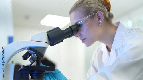 A pathologist in a hospital lab examines a stained tissue specimen under a microscope, identifying cellular abnormalities to provide a definitive diagnosis for a patient's condition.