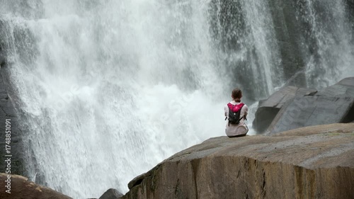 Loopable video of a young woman sitting in front of Rainbow Falls, a massive waterfall in North Carolina.