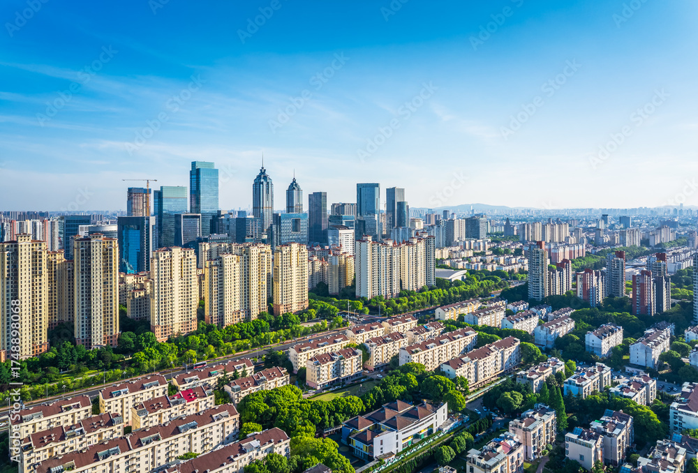 Naklejka premium Aerial view of a modern residential district with the commercial city skyline under a clear blue sky in Suzhou. Urban development and real estate background.