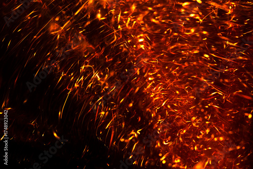 Fiery orange and yellow spark trails creating a vibrant, energetic pattern against a dark backdrop.