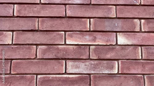 Moving shot of a red brick wall with realistic texture and natural light. ideal for use as a background video, texture footage in design and construction projects.