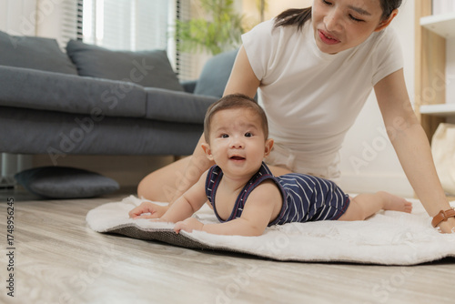 Foto A baby enjoys tummy time on a soft mat while the mother stays close, encouraging him with a warm smile