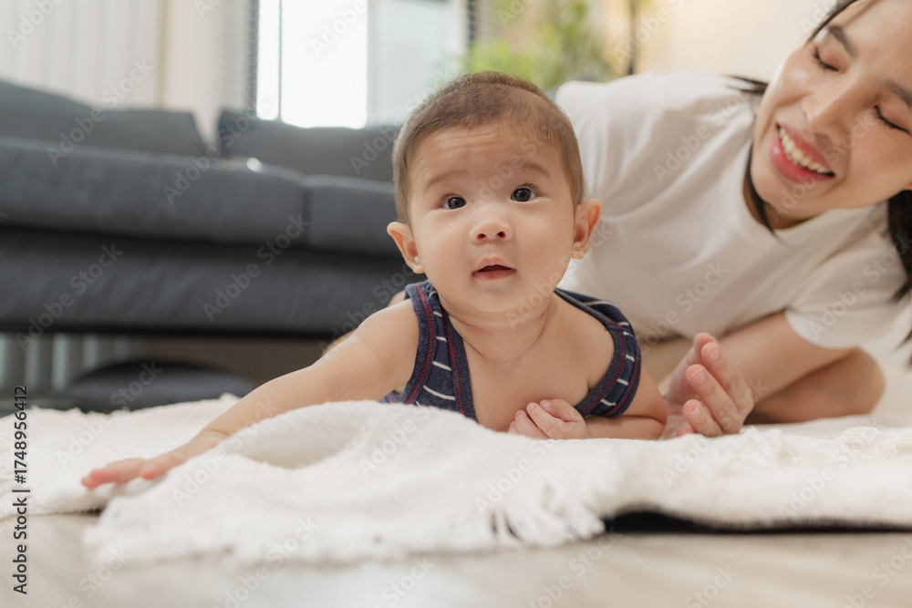 Fototapeta premium A loving mother spends quality time with her baby, helping him practice tummy time, rolling, and sitting up. These tender moments reflect family bonding, care, and child development at home.