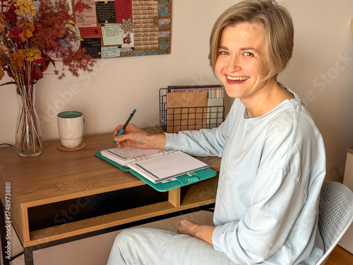 Woman sitting at a wooden desk, writing in a notebook
