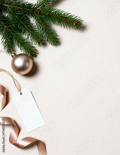 Spruce branch with pearl ornament and blank gift tag on beige