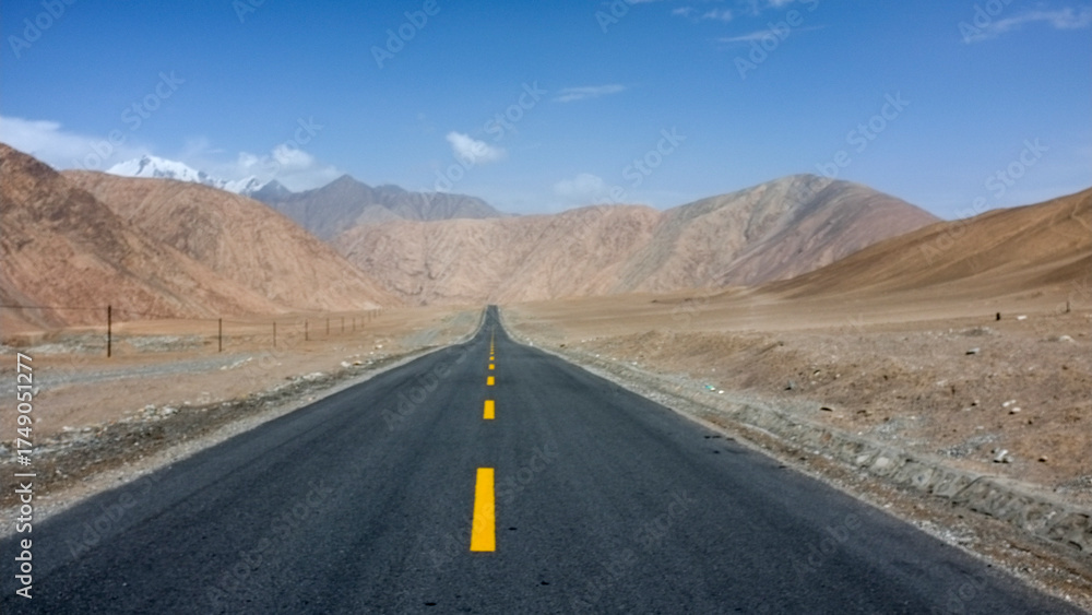 Naklejka premium Long straight road stretching through arid mountainous area
