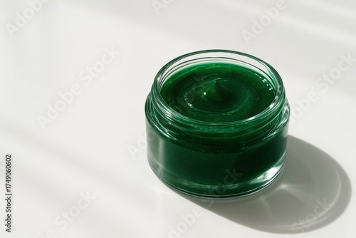 Bright green spirulina facial gel in a clear glass jar illuminated by natural sunlight — minimal skincare composition highlighting texture, freshness, and vibrant natural beauty