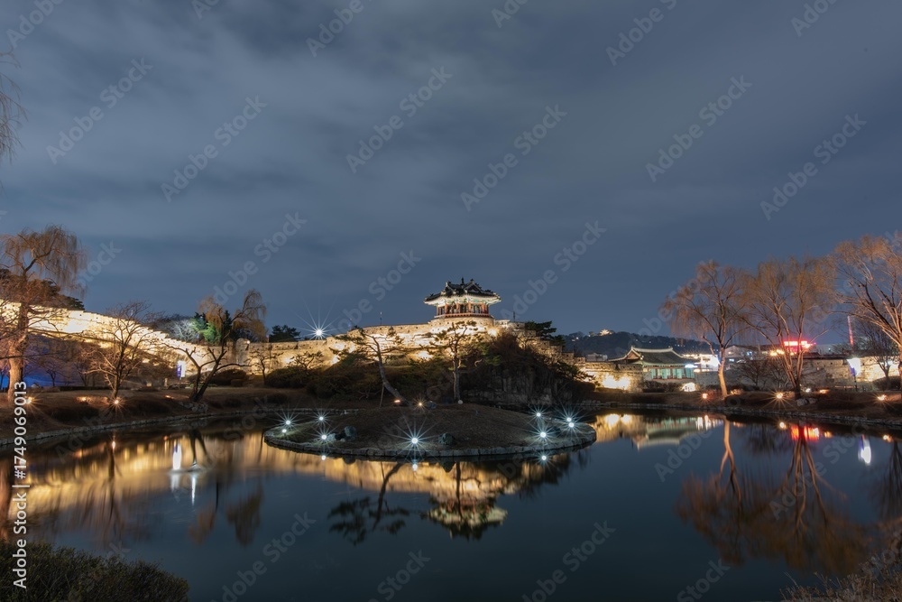 Fototapeta premium Captured this serene view of Hwaseong Fortress' Banghwasuryujeong in March. The calm pond and traditional architecture shine under the dark sky with a great reflection.