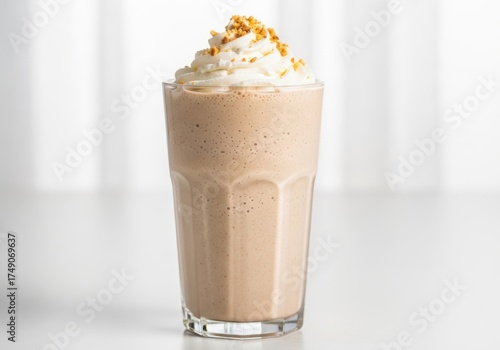 Tall glass of creamy peanut butter milkshake topped with whipped cream and sprinkles
