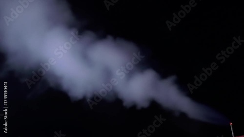 Dense smoke plume illuminated against a dark black background.