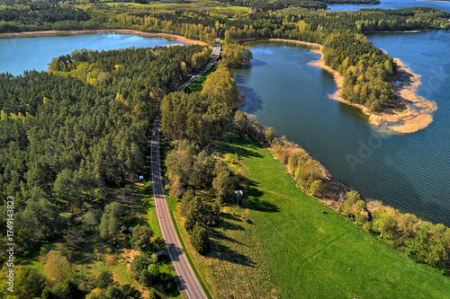 Fototapeta Naklejka Na Ścianę i Meble -  Summer aerial view of a scenic road winding through forest by a Masurian lake