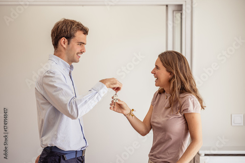 Young beautiful woman receiving keys to new apartment from real estate agent
