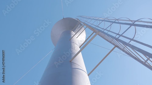 Water tower viewed from below, showcasing structural details and blue sky, with gradual upward camera movement emphasizing height and engineering design elements