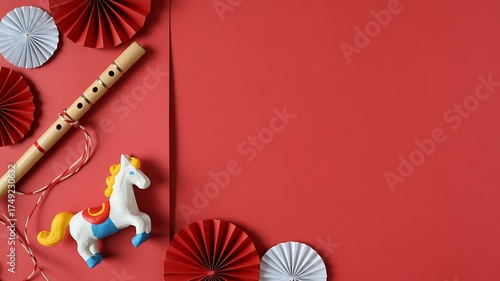 Bengali festival flat lay with toy horse, wooden flute and red white paper rosettes