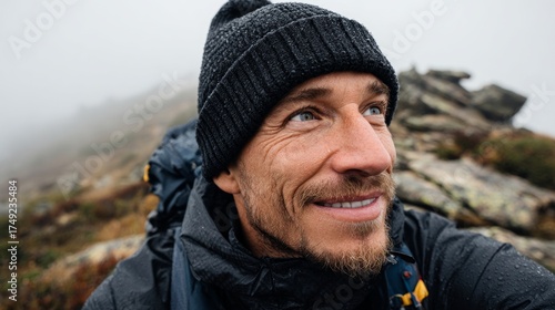Man smiling at camera outdoors in mountainous area.
