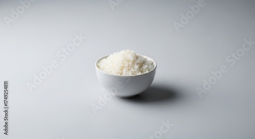 White bowl of cooked rice on plain grey background