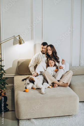 Family enjoying christmas playing with dog on couch