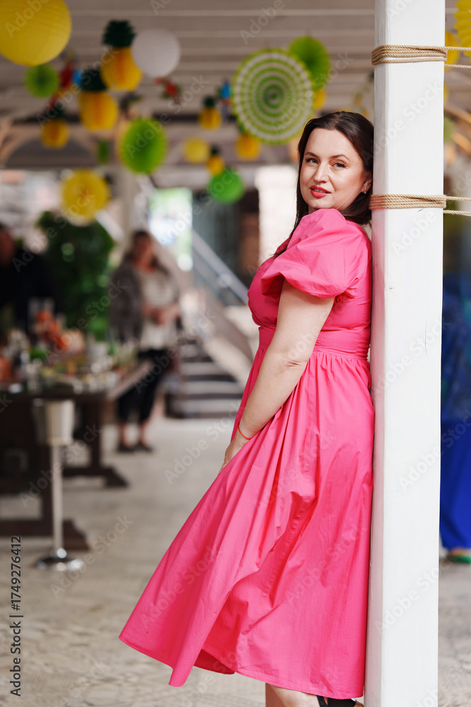 Obraz premium Woman in a pink dress poses gracefully at a vibrant outdoor gathering