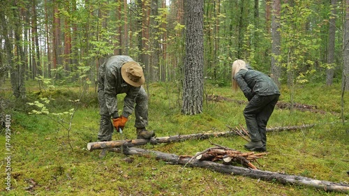 A man and a woman, forest rangers, are clearing the forest of dry and old trees. Clearing the forest of fallen tree trunks. Forest maintenance. Tourists are gathering firewood for a campfire. The man