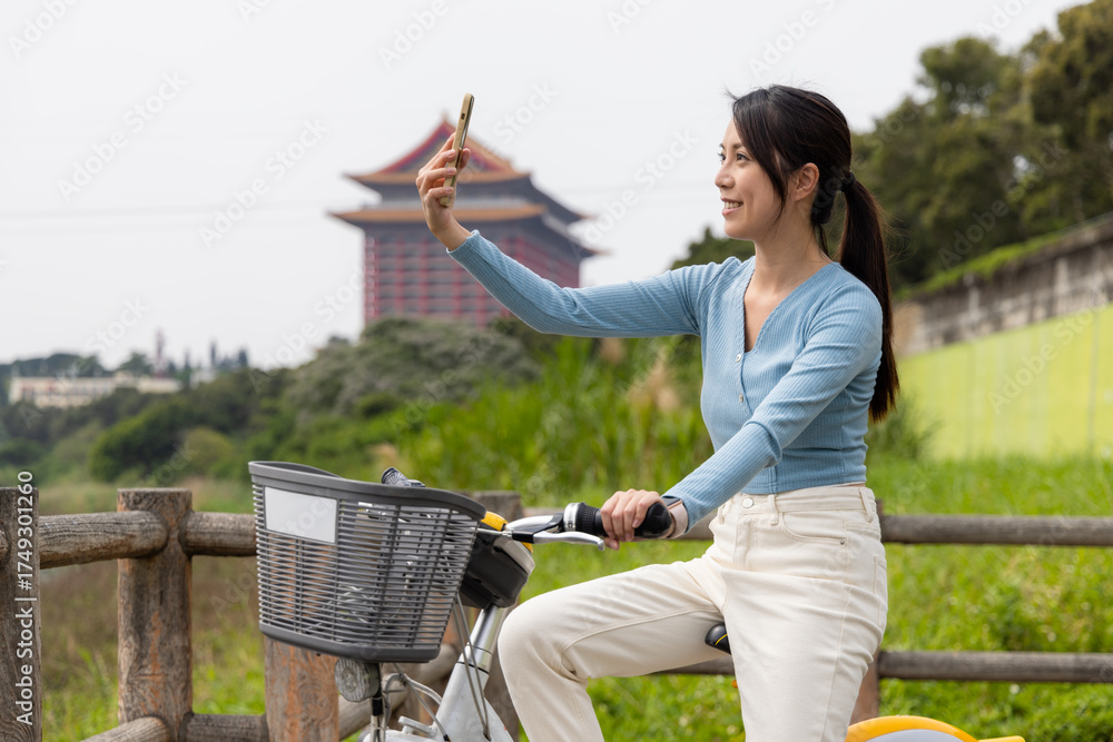Naklejka premium Woman cycling and taking selfie on phone in Taipei city