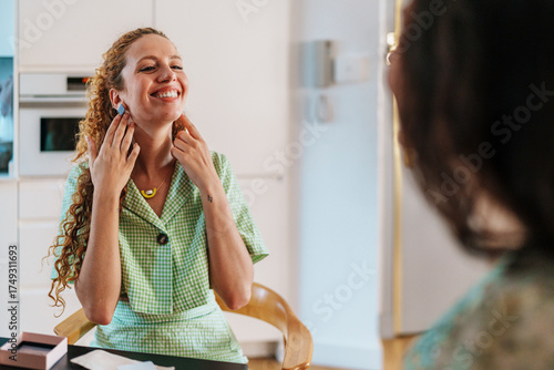 Woman smiling while trying on earrings in a bright home interior