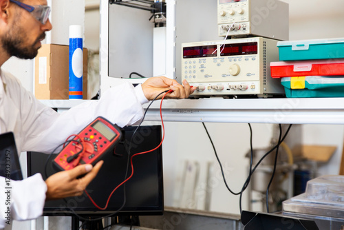 Lab technician testing electronics with voltage meter in innovation lab